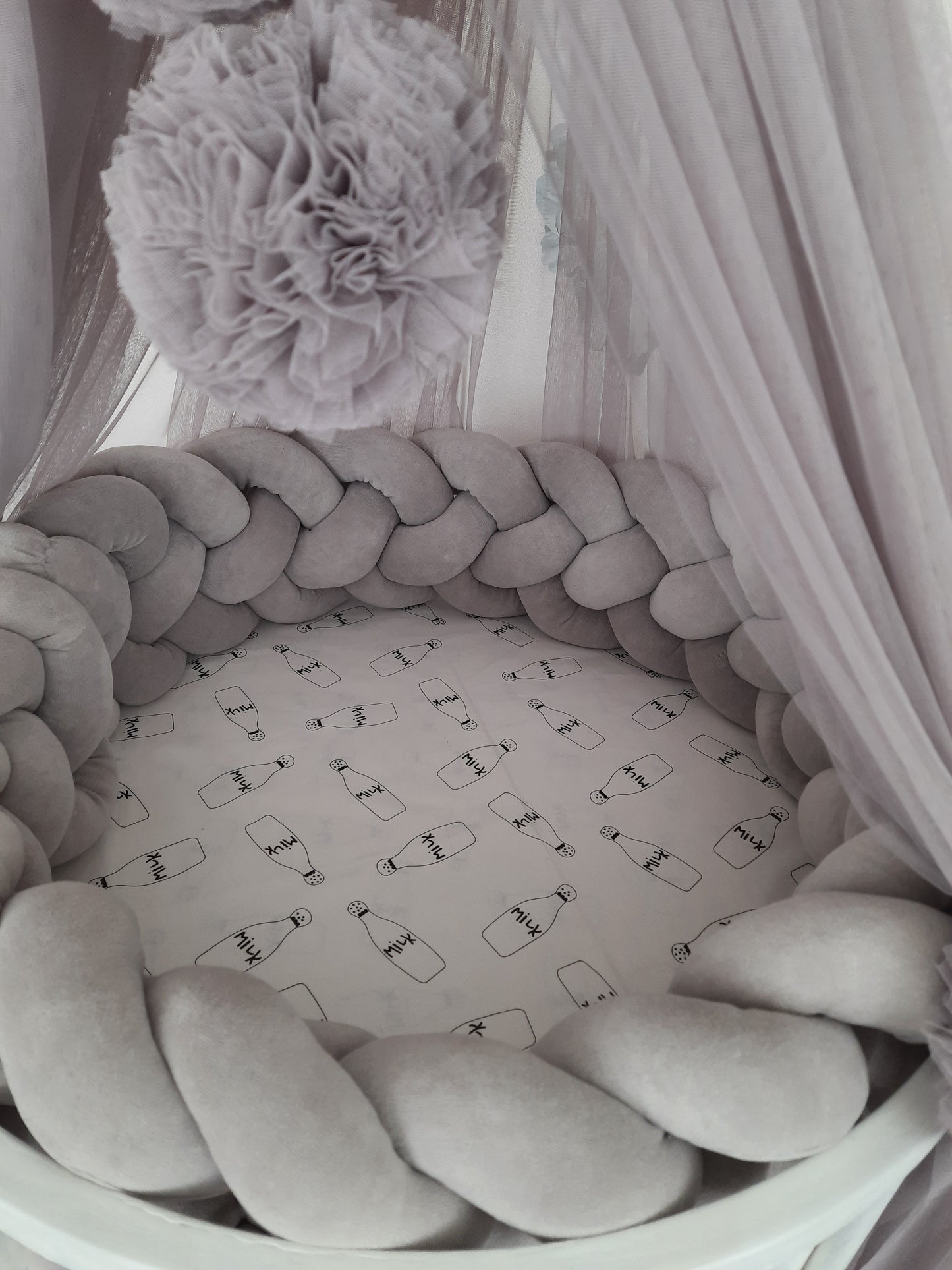 Oval crib with gray canopy with pom poms and gray Braided Crib Bumper - Weaving in 4 Strips. Close up