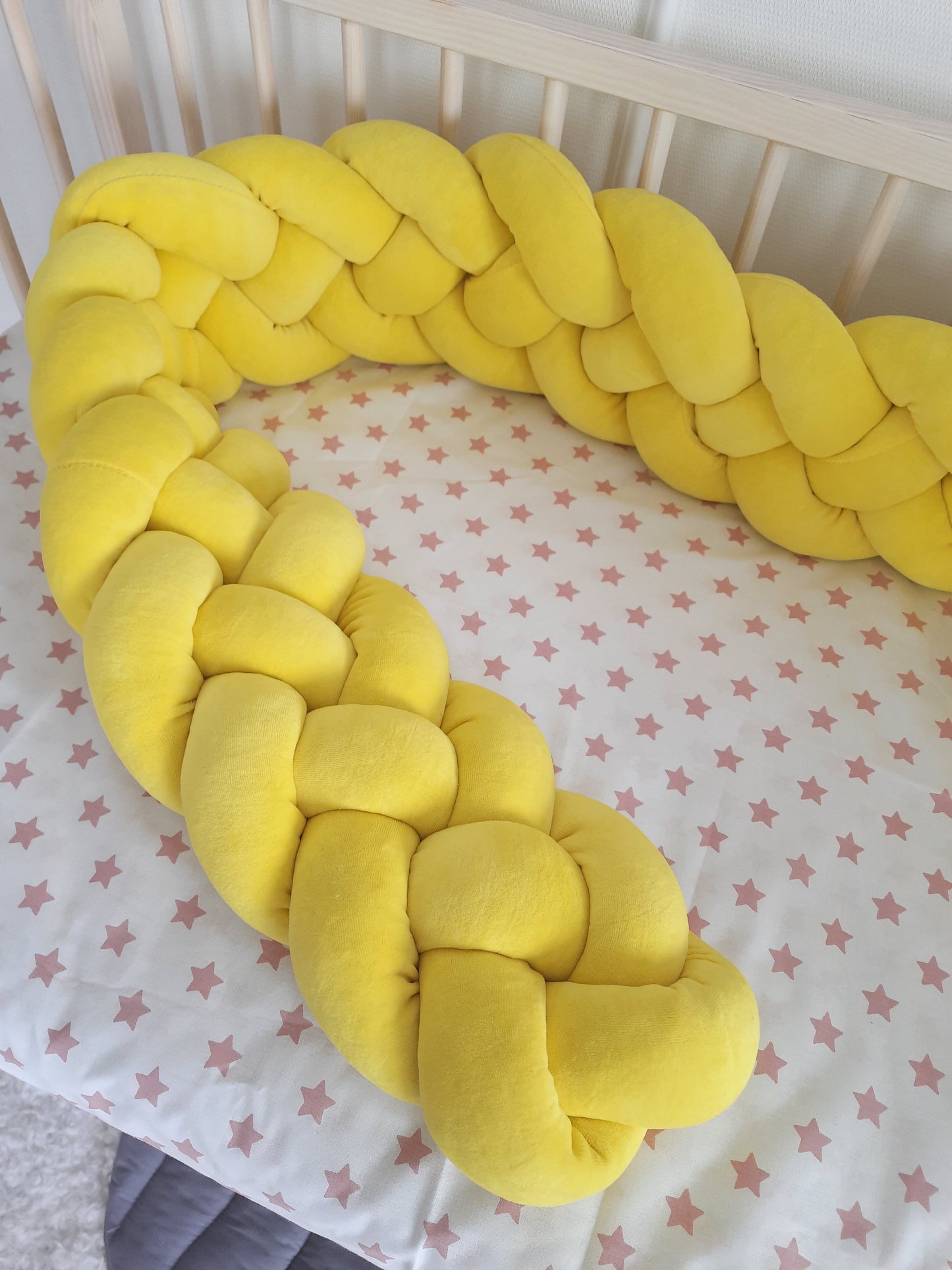 Yellow braided bumper on the crib. Close-up