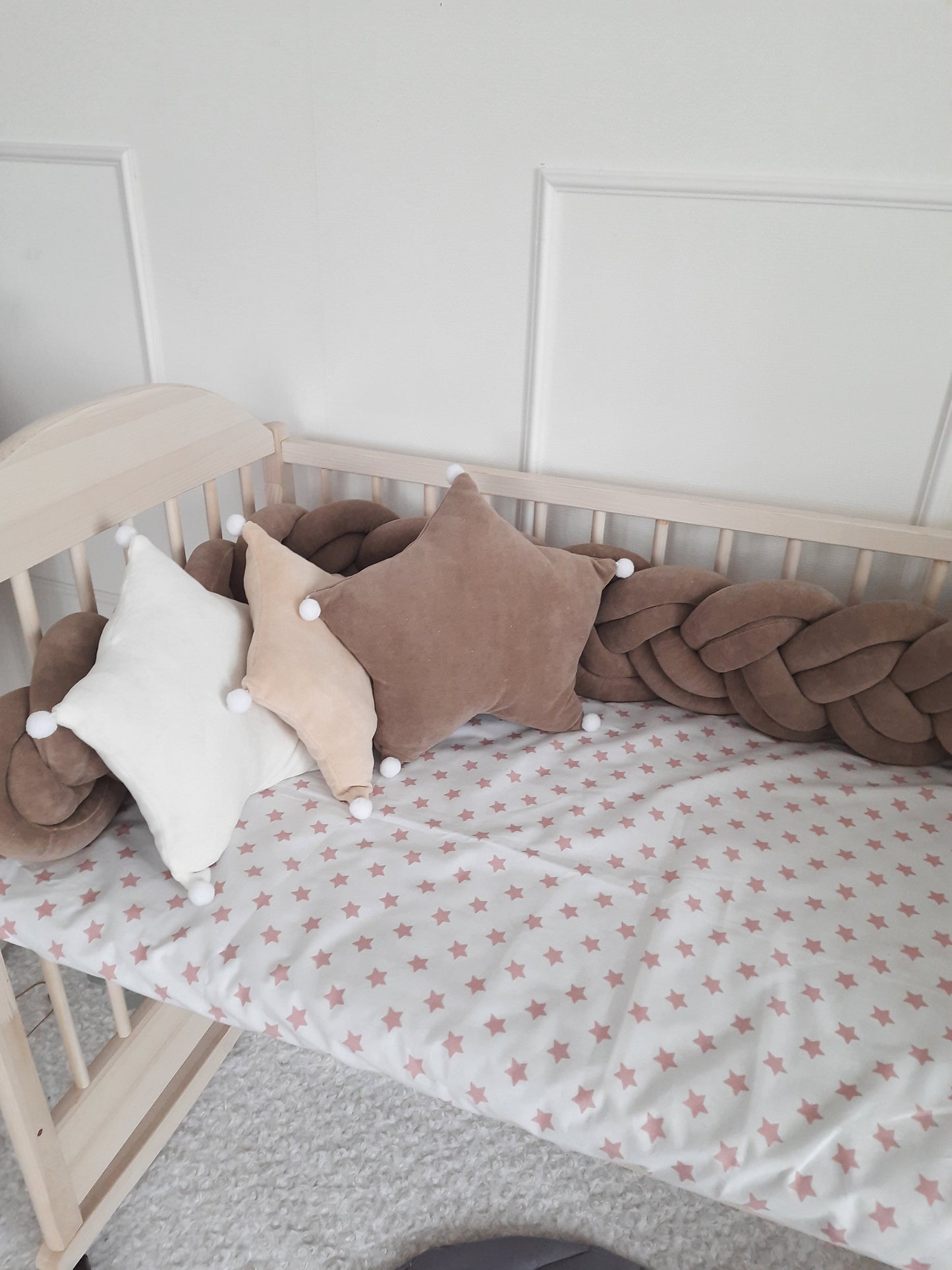 Brown double braided crib bumper with white, coffee and brown star pillows on the crib.