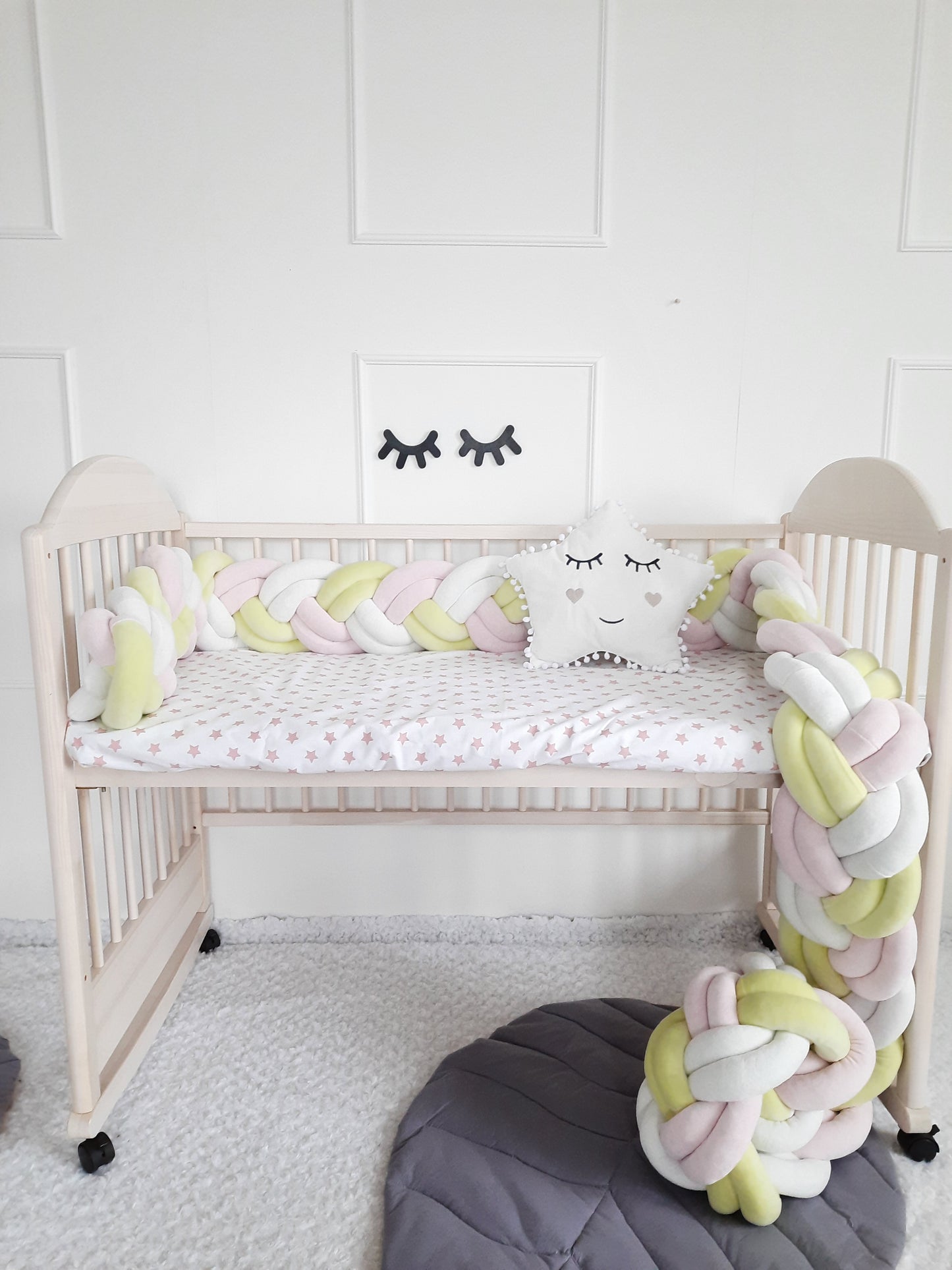 Double braided cot bumper in 3 diffrent colors and white star pillow on the crib. Front side 