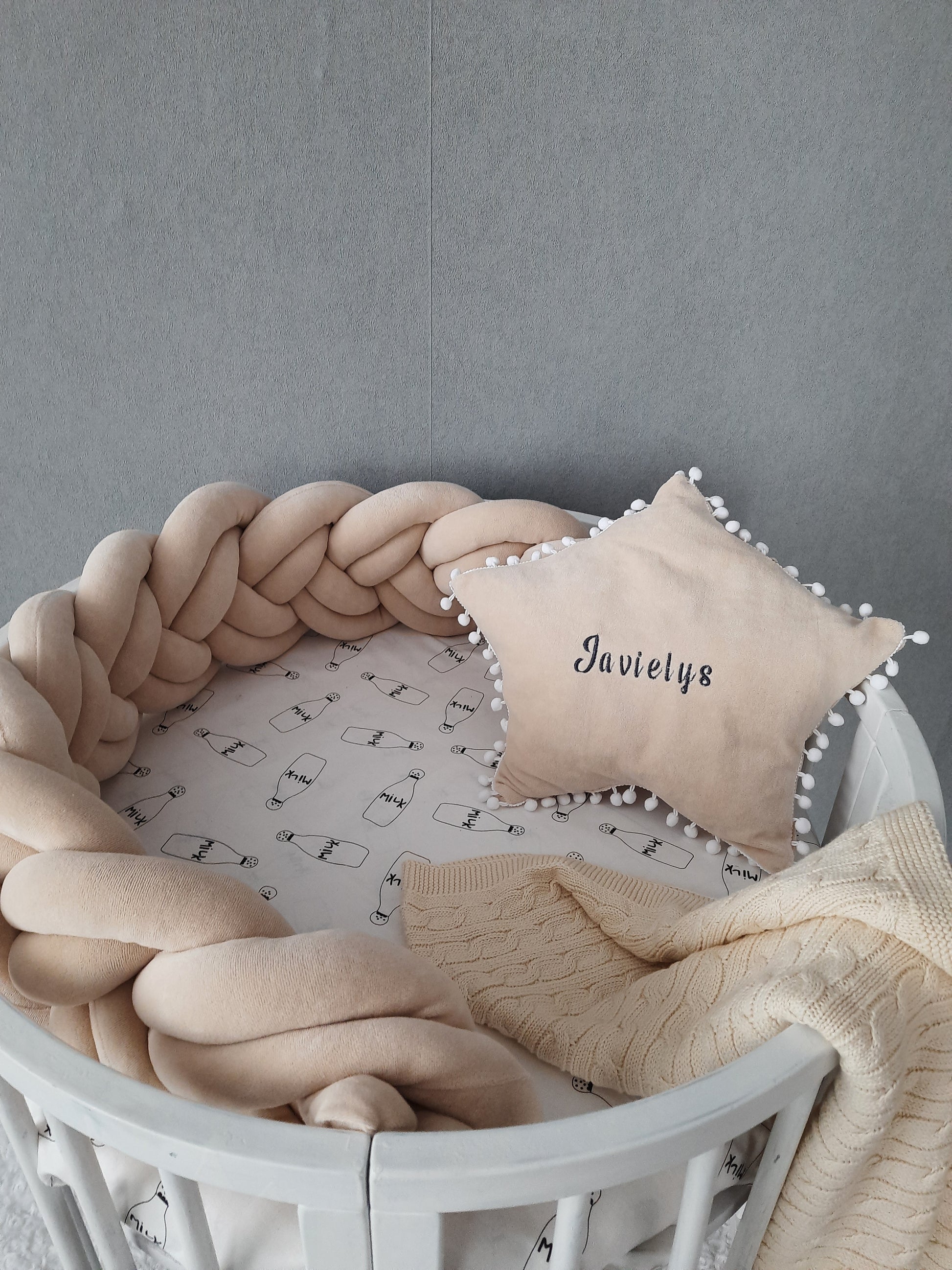 Short double braided crib bumper in cream color and star pillow with embroider of baby name on the circular crib