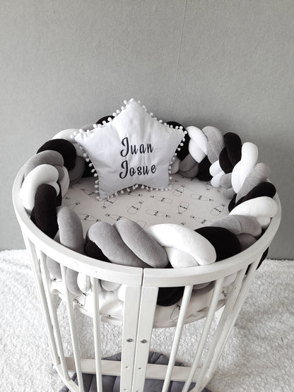 Double braided cot bumper and white star pillow with embroider of baby name on the oval crib