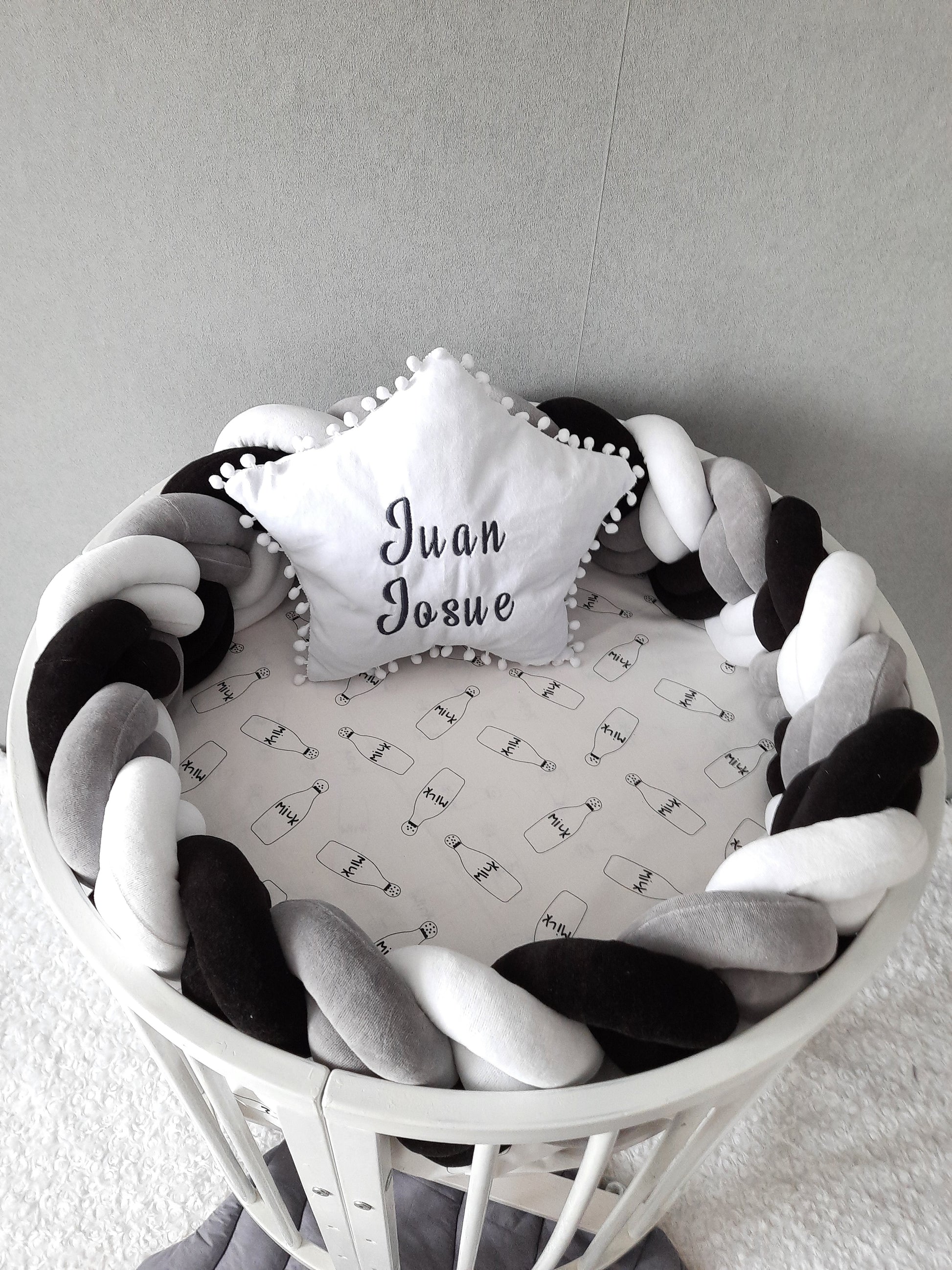 Double braided cot bumper and white star pillow with embroider of baby name on the oval crib