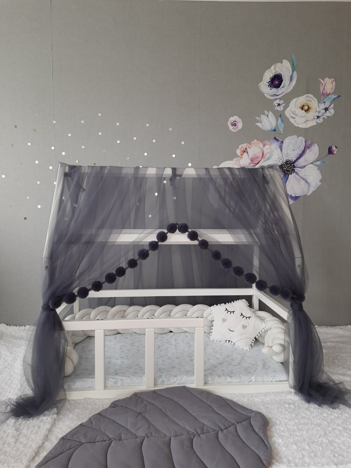 Dark gray montessori canopy for nursery. White braided bumper and star pillow in the bed