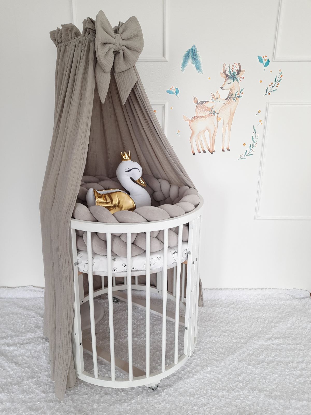 Gray muslin canopy for crib. Braided bumper and swan pillow on the crib. 