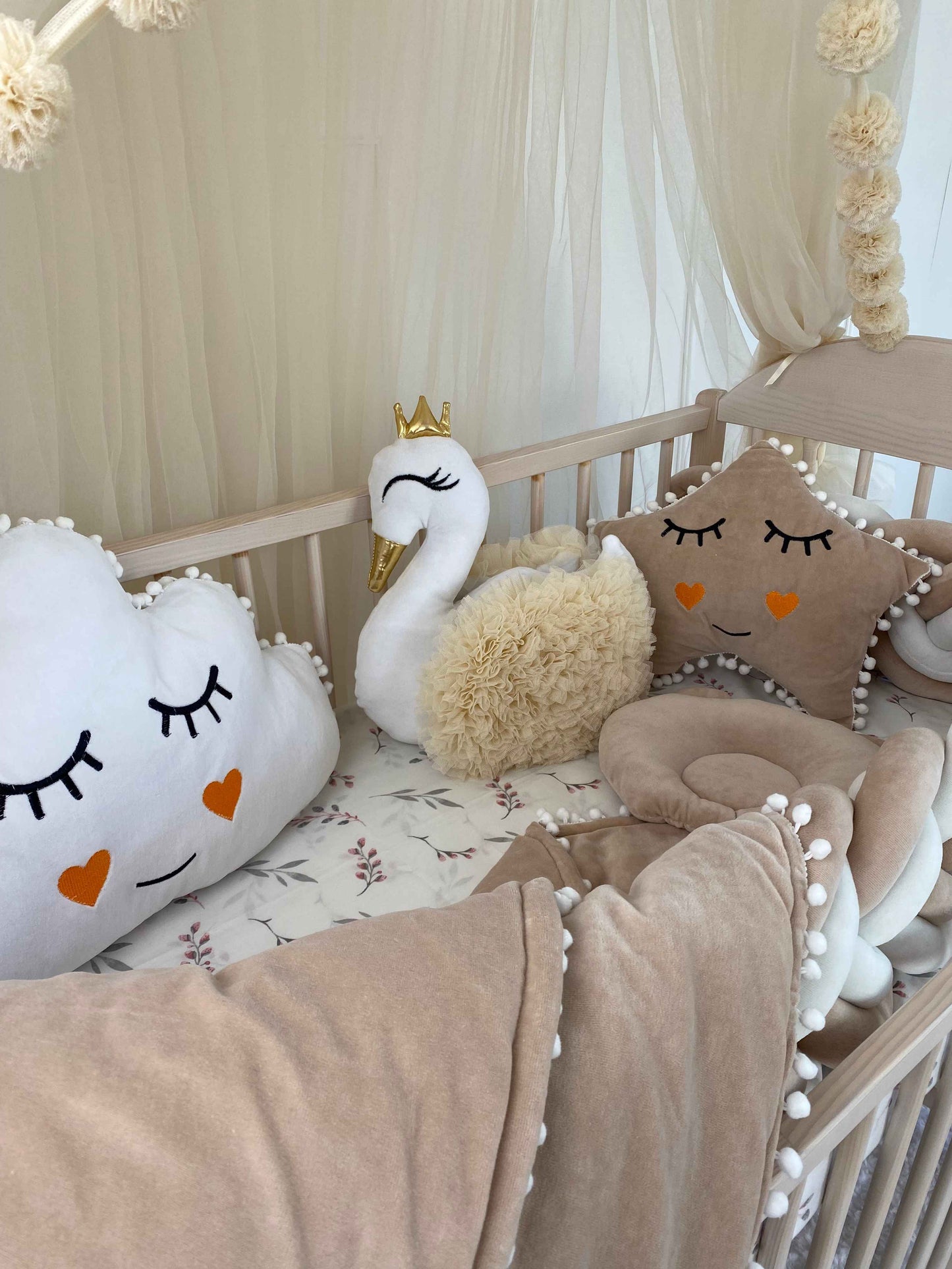 White swan pillow with cream color wings on the crib. 