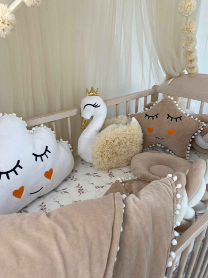 White swan pillow with cream color wings on the crib. 