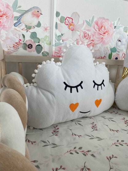 White cloud pillow with cute face on the crib. 