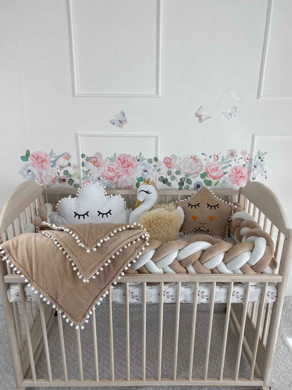 Cot bumper, 3 plush pillows and blanket on the crib. Cream and white colors. Front side.