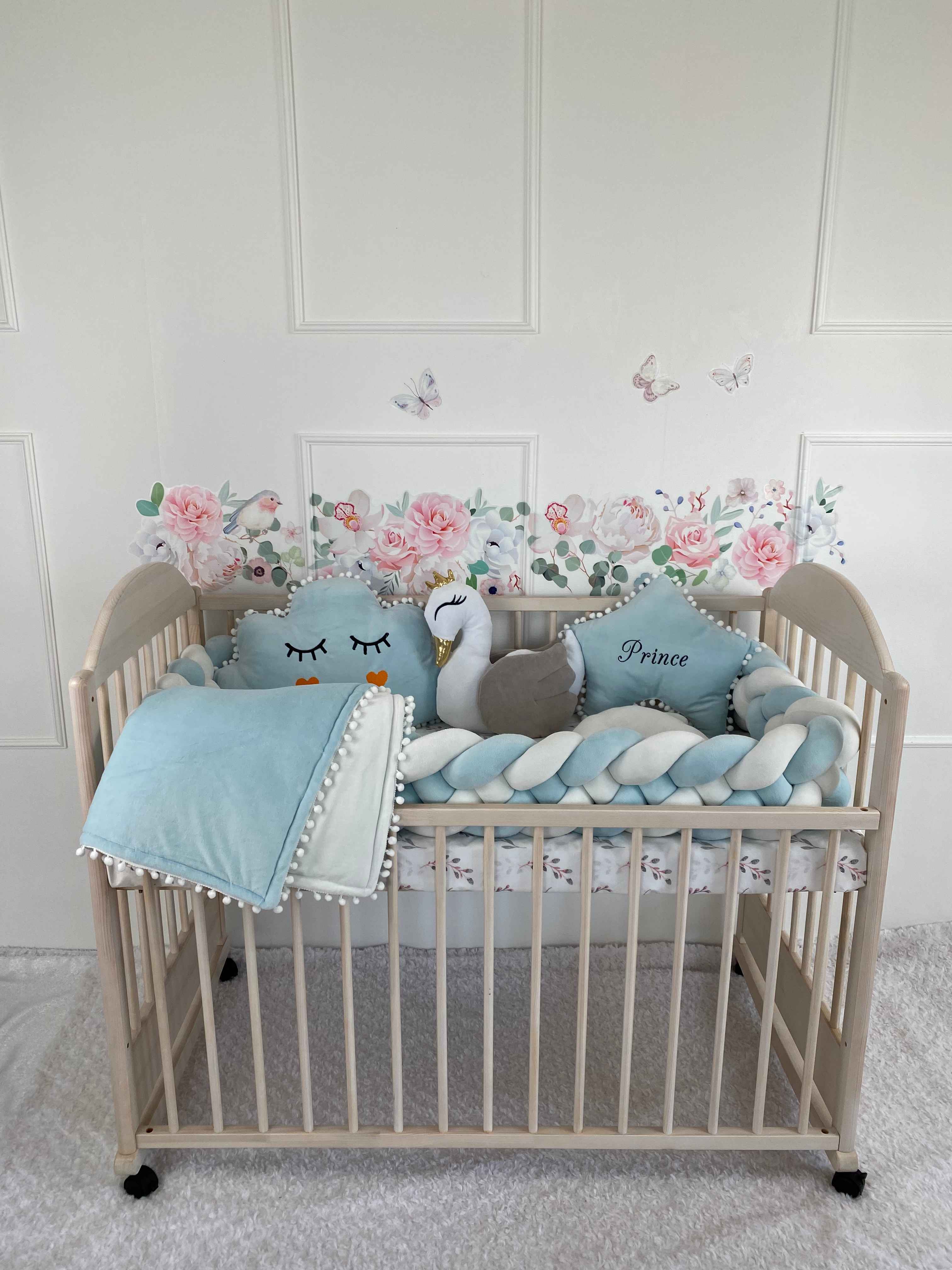 Crib set in blue and white colors on the crib. Braided bumper, blanket, star, swan and cloud pillows.