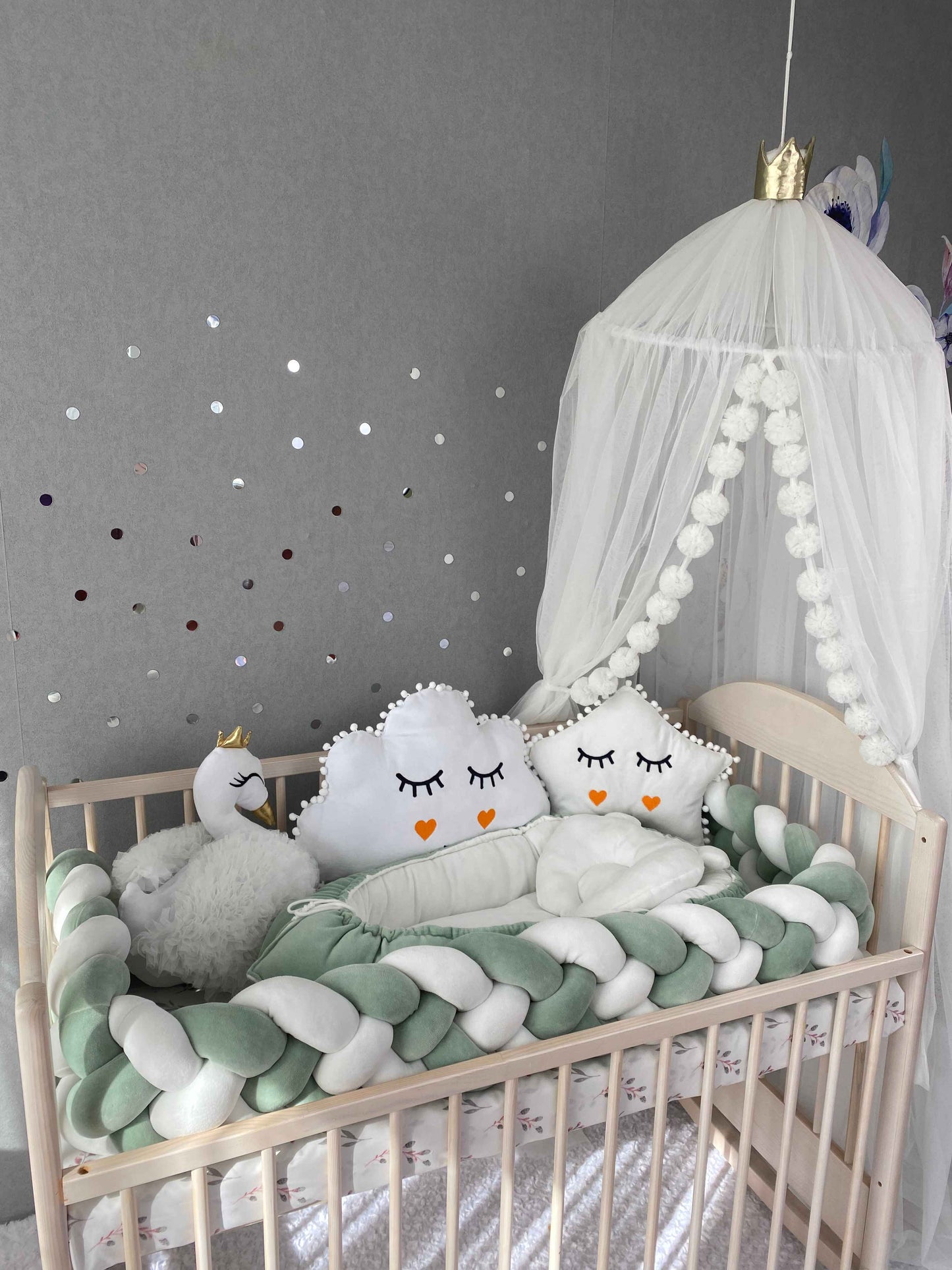 Braided cot bumper, baby nest, star pillow with custom embroidery, cloud and swan pillows on the crib. White canopy over the bed 