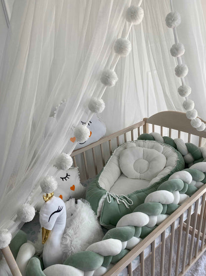 Baby nest, swan pillow in cot. White canopy over the bed. 