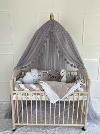 A charming baby crib adorned with a canopy and a plush white pillows, perfect for a cozy and stylish nursery setup