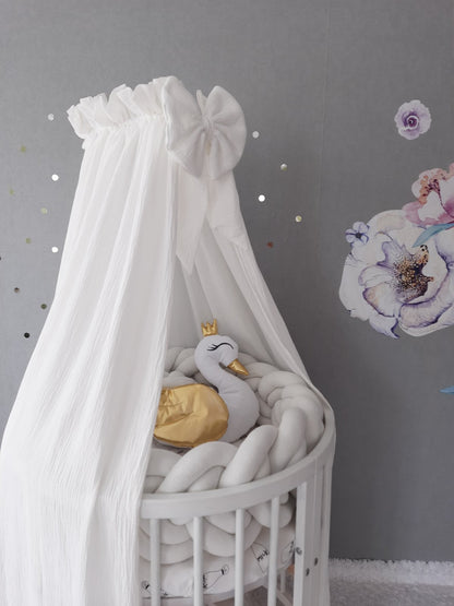 White Muslin Canopy for crib. White braided cot bumper and swan pillow on the crib