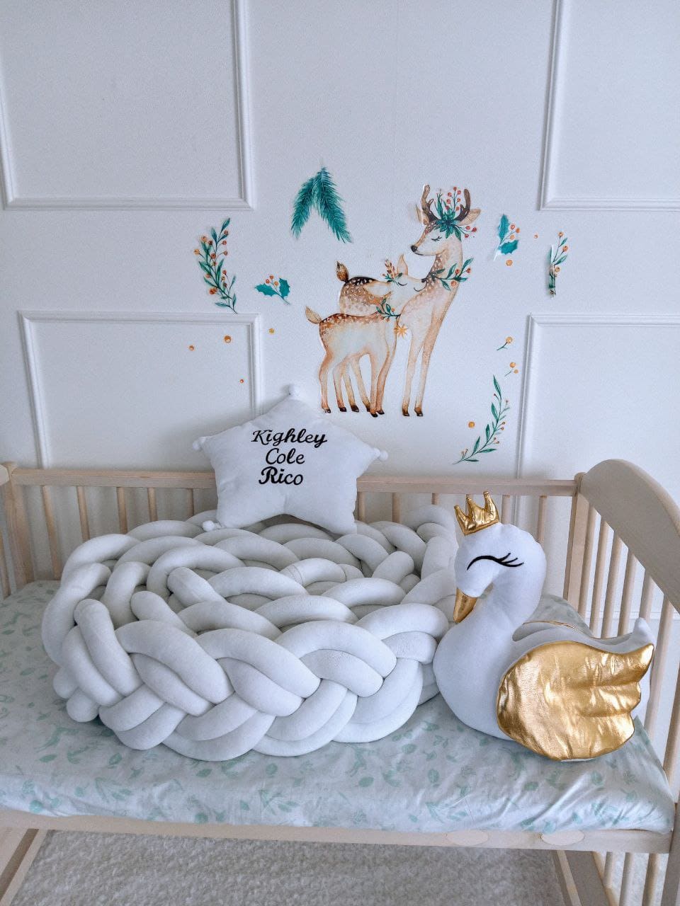 Double braided cot bumper, star pillow with embroider and swan pillow on the crib. White color, front side