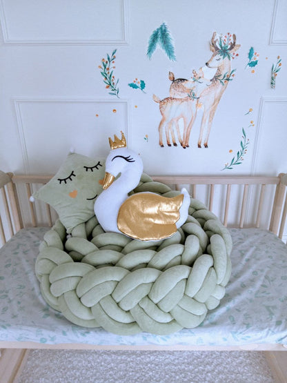 Light olive braided bumper and white swan pillow on top of it. Front side