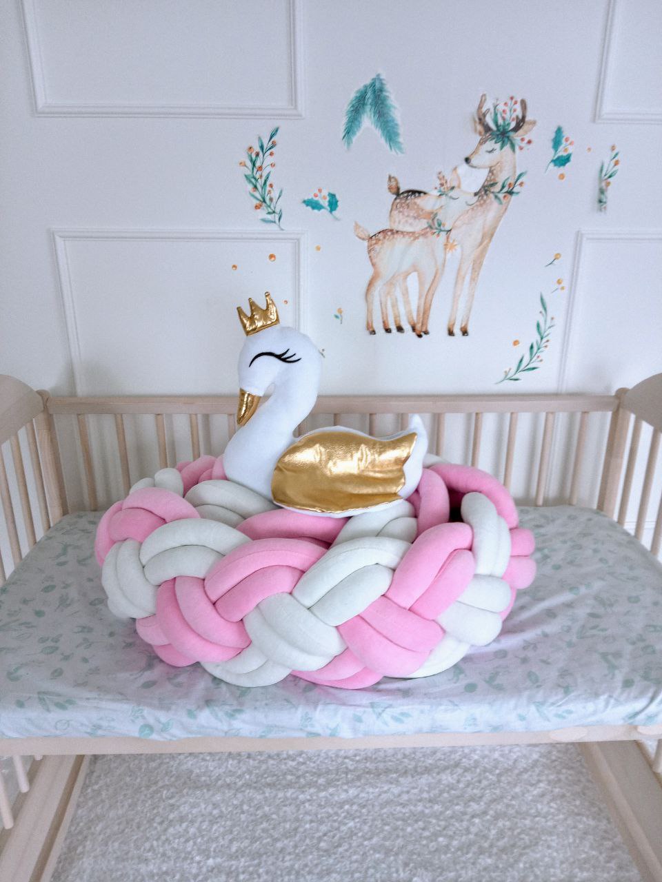 Double braided crib bumper in white and pink color with swan pillow on crib