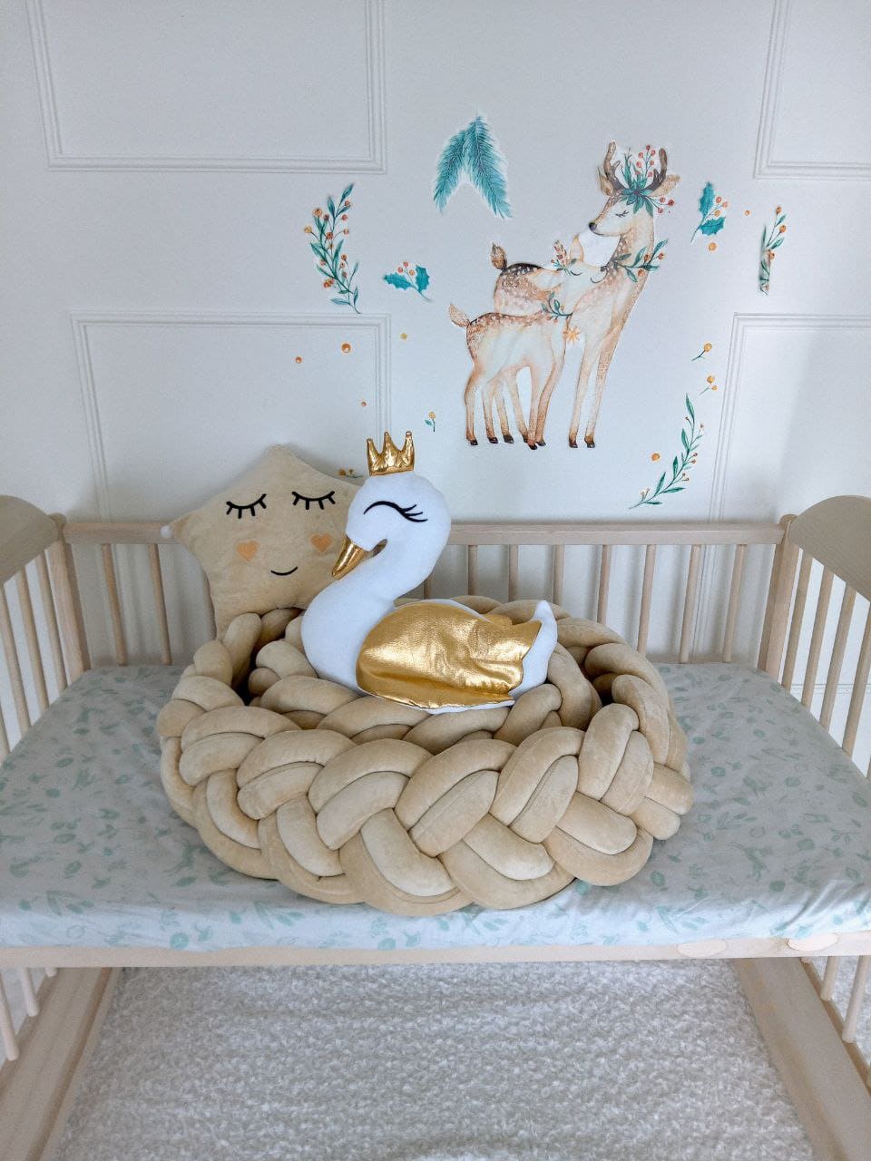 Vanilla star pillow and white swan pillow on top of the vanilla braided crib bumper. Front side