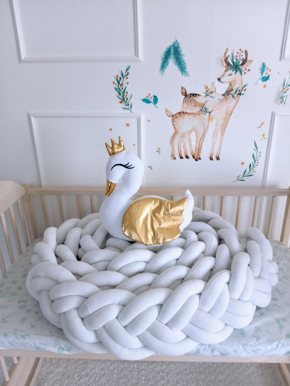 Swan pillow on the top of white double braided crib bumper