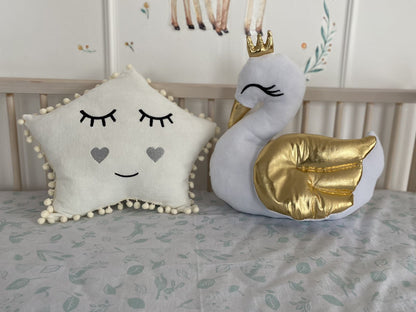 Star and swan pillows on the crib. White color, front side.