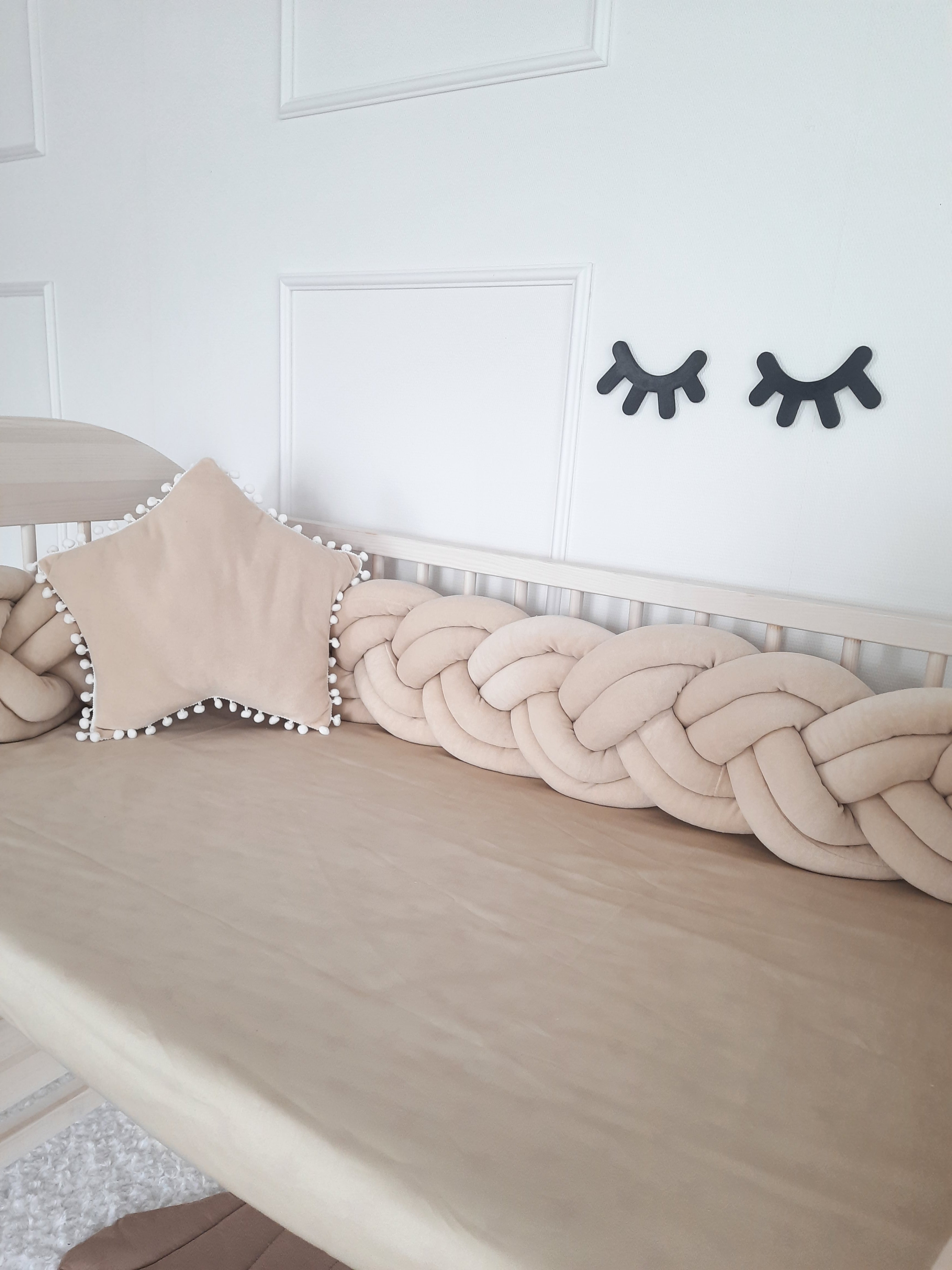 Coffee Double Braided Bumper with coffee star pillow on the crib. Front side slightly angled from the right, close up