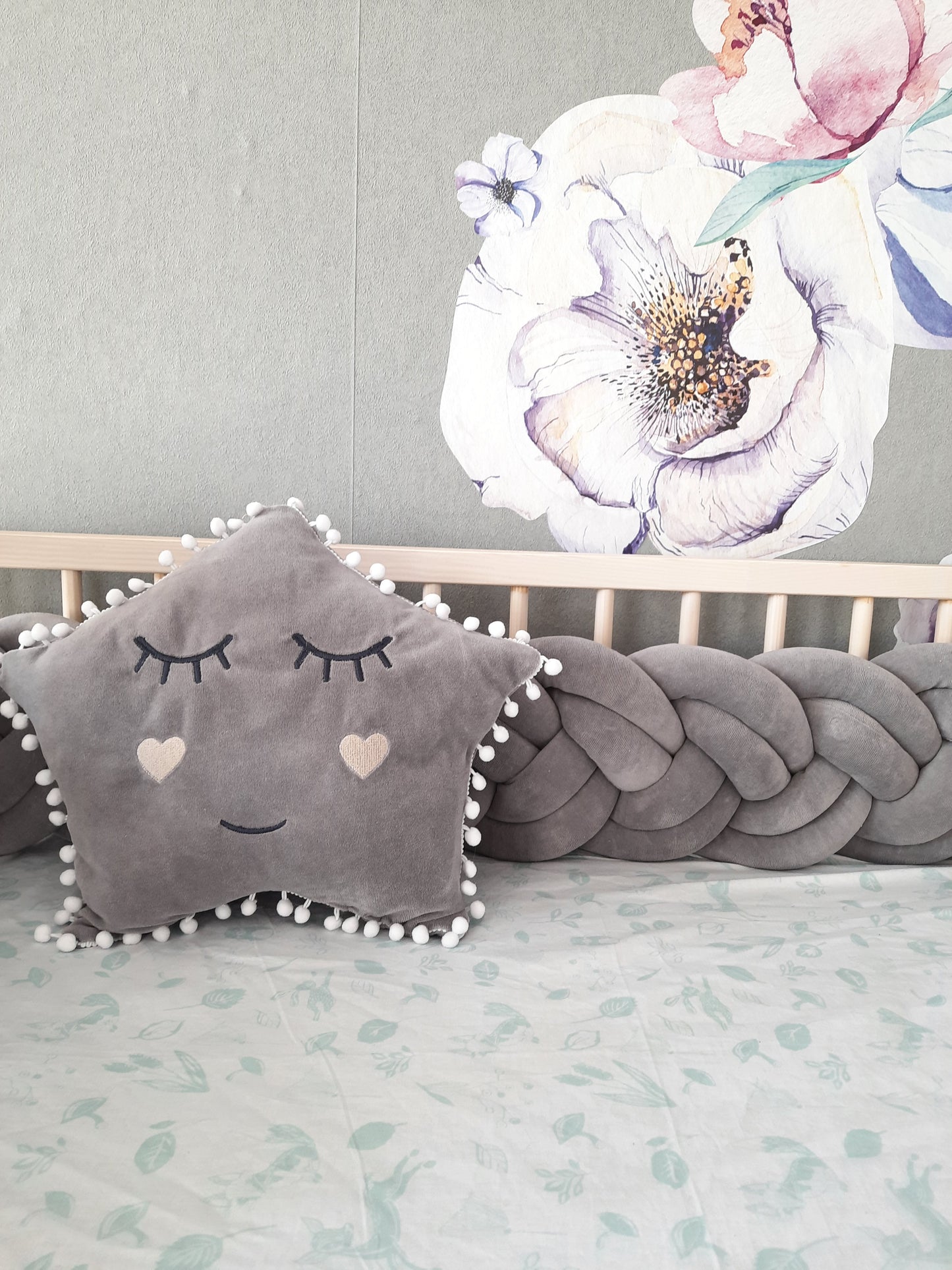 Gray double braided crib bumpers with gold gray star pillow on the crib. Front side, close up