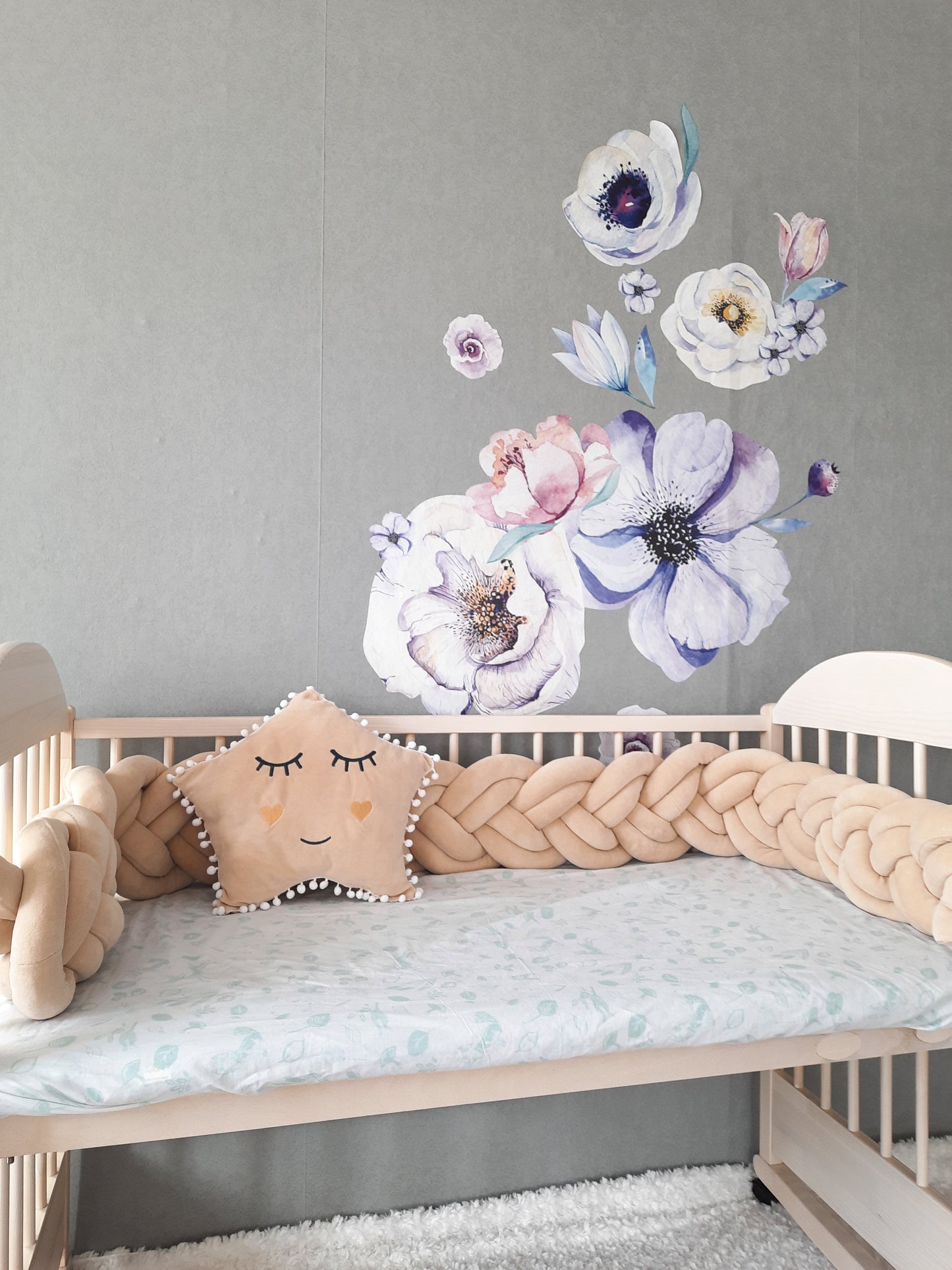 Double braided cot bumper with star pillow on the crib. Cream color