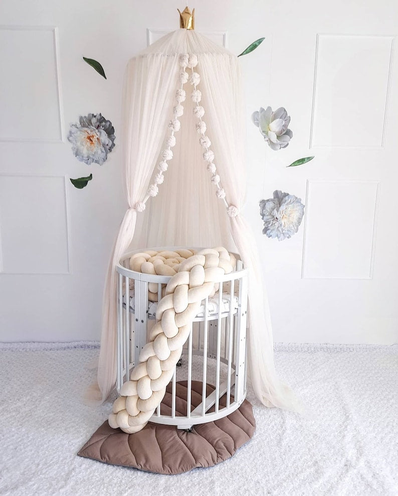 Ivory Nursery Canopy with ivory double braided bumper on the crib. In white nursery room. Front side.